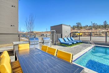 The deck has a pool and a table with chairs and a grill